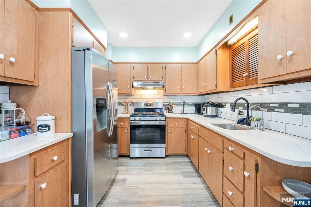 728 Devon Street Kearny, NJ 07032 - Photo 8 of 26 a kitchen with stainless steel appliances granite countertop a refrigerator a sink dishwasher a stove and white countertops with wooden floor
