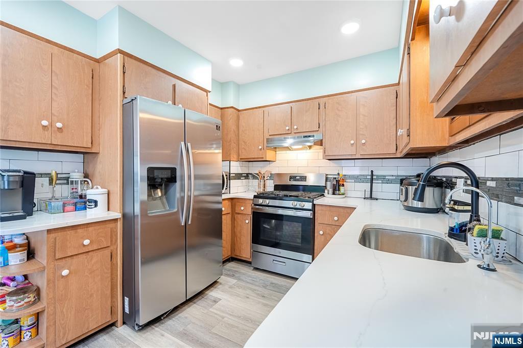 728 Devon Street Kearny, NJ 07032 - Photo 9 of 26 a kitchen with granite countertop a refrigerator a sink a stove and wooden cabinets