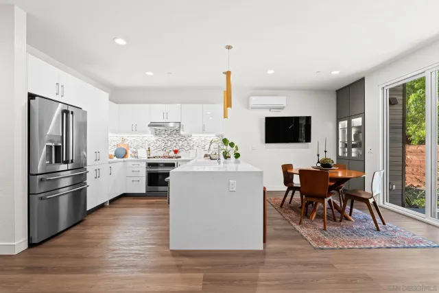 a kitchen with stainless steel appliances kitchen island granite countertop a stove top oven a sink a dining table and chairs