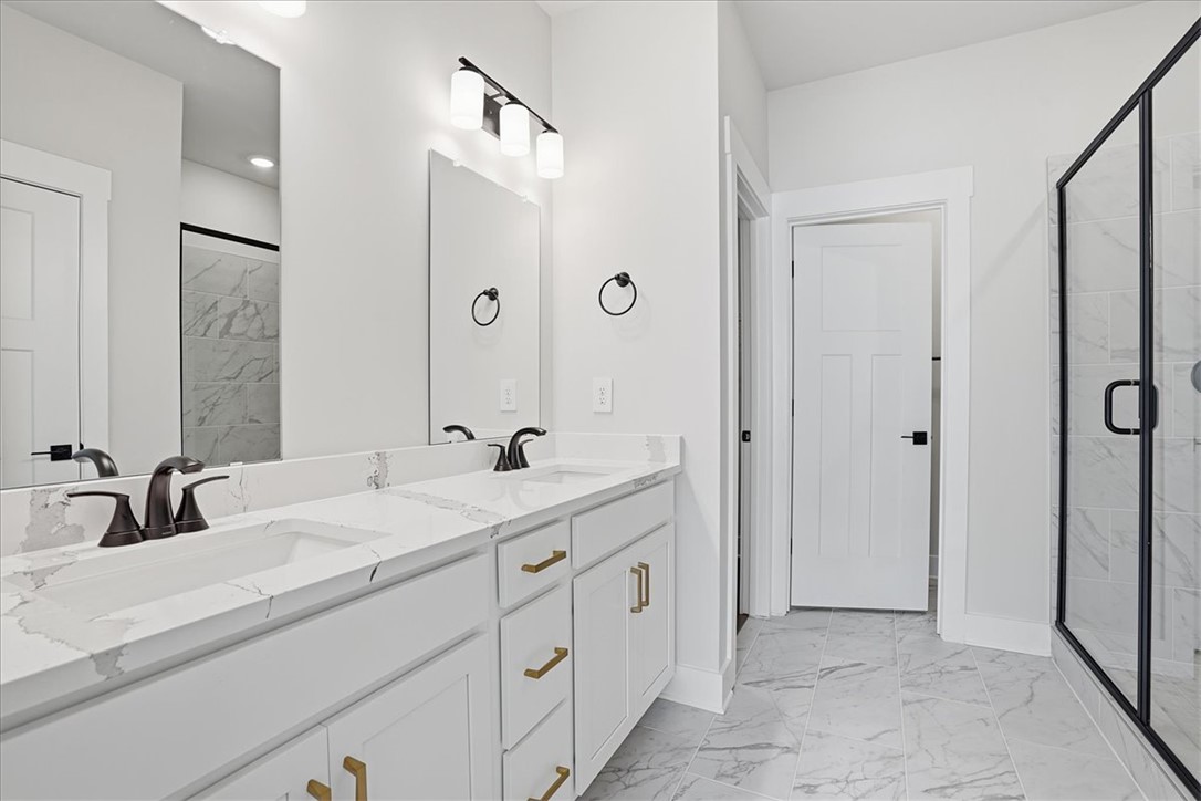 343 Allingham Road Piedmont, SC 29673 - Photo 24 of 37 Marble-patterned tile flooring enhances this well-appointed primary bathroom featuring a dual vanity and glass-enclosed shower.