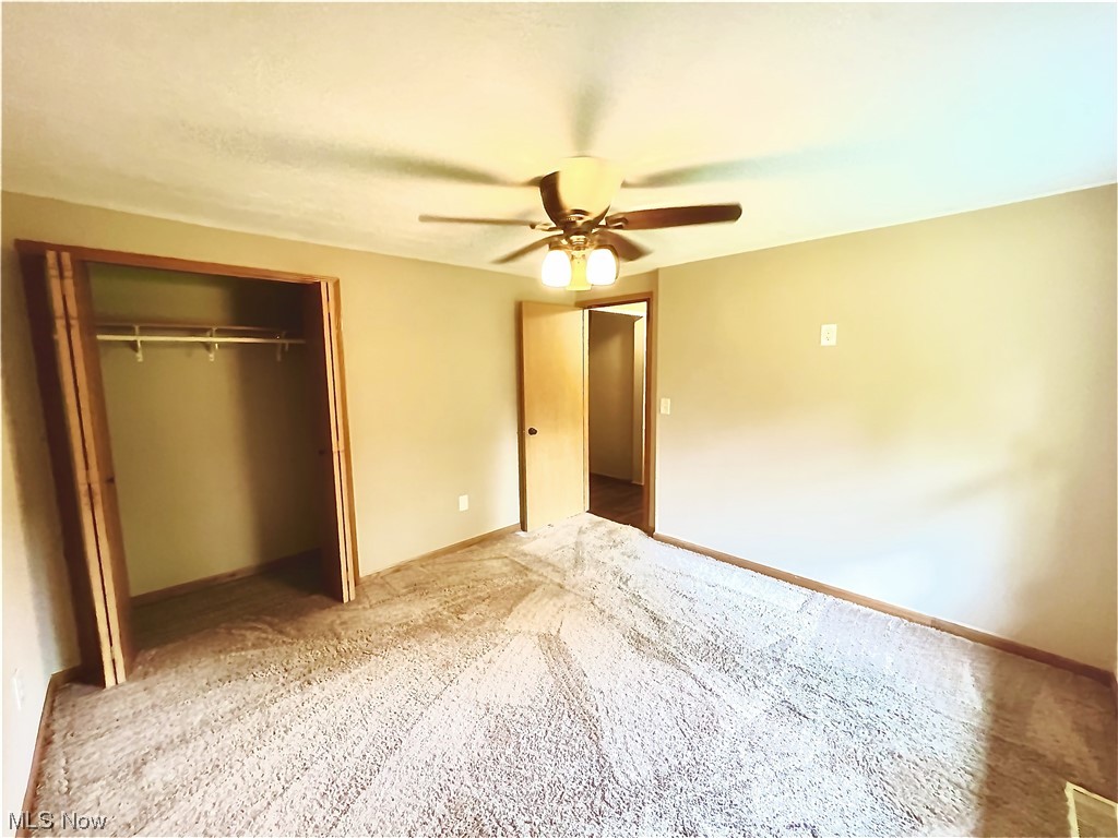 3122 Bedrock Road Northwest Dellroy, OH 44620 - Photo 19 of 23 Unfurnished bedroom featuring a closet, light colored carpet, and ceiling fan