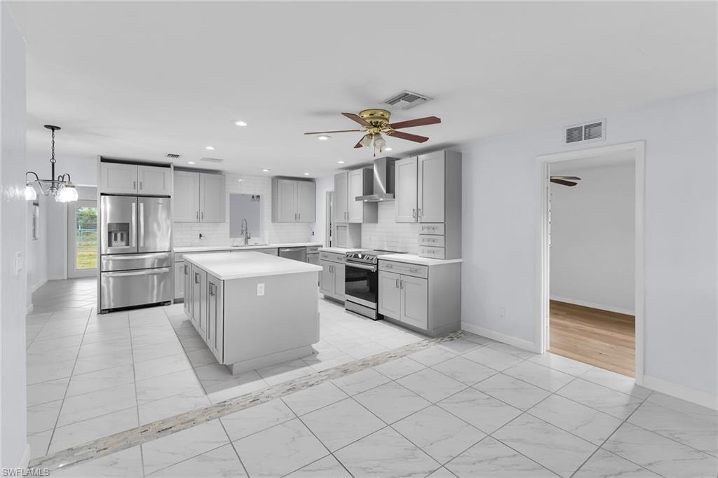 4502 22nd Place Southwest Naples, FL 34116 - Photo 1 of 30 Kitchen with light marble finish flooring, stainless steel appliances, light countertops, backsplash, and a kitchen island