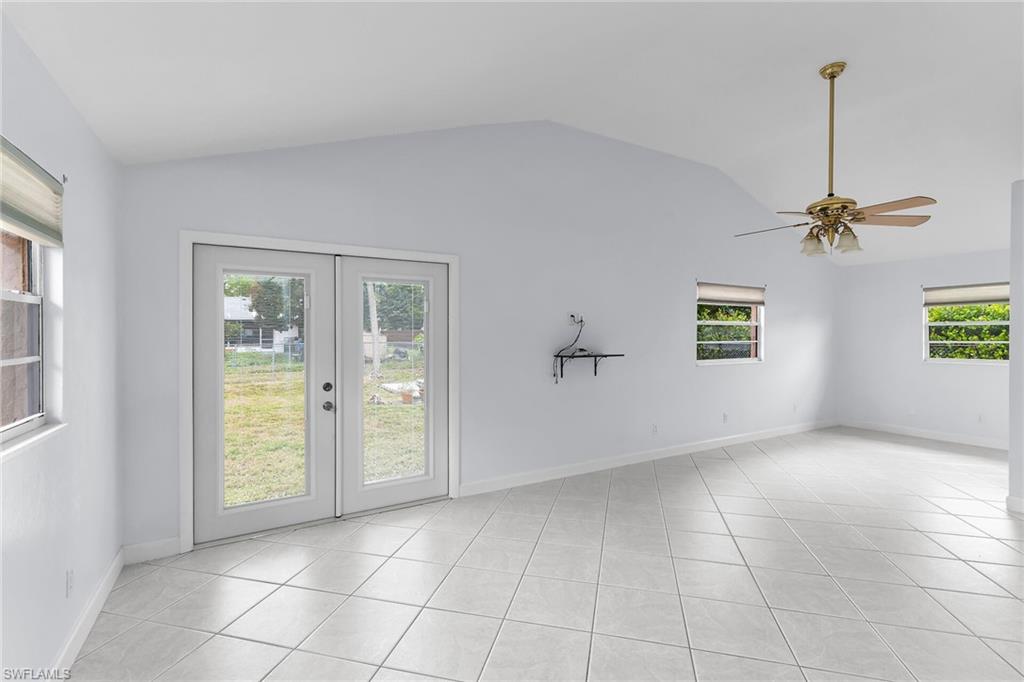 4502 22nd Place Southwest Naples, FL 34116 - Photo 12 of 30 Empty room with a ceiling fan, light tile patterned floors, french doors, and lofted ceiling