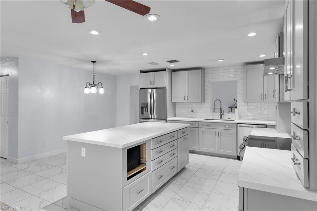 4502 22nd Place Southwest Naples, FL 34116 - Photo 5 of 30 Kitchen with light marble finish floors, recessed lighting, light stone counters, stainless steel fridge with ice dispenser, and a center island