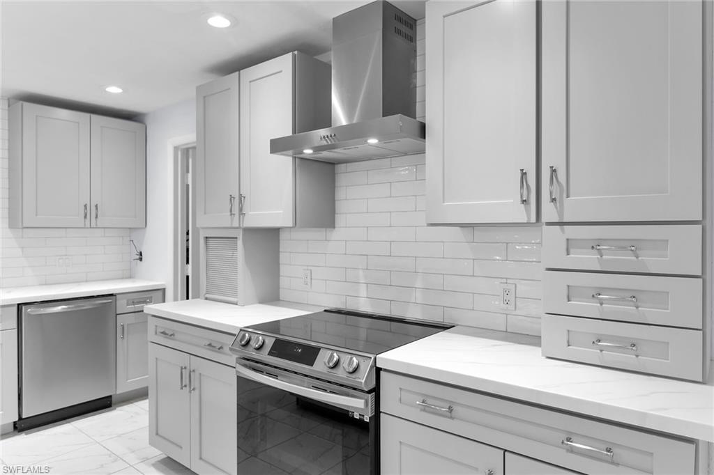4502 22nd Place Southwest Naples, FL 34116 - Photo 6 of 30 Kitchen with stainless steel appliances, wall chimney exhaust hood, light marble finish flooring, light stone counters, and decorative backsplash