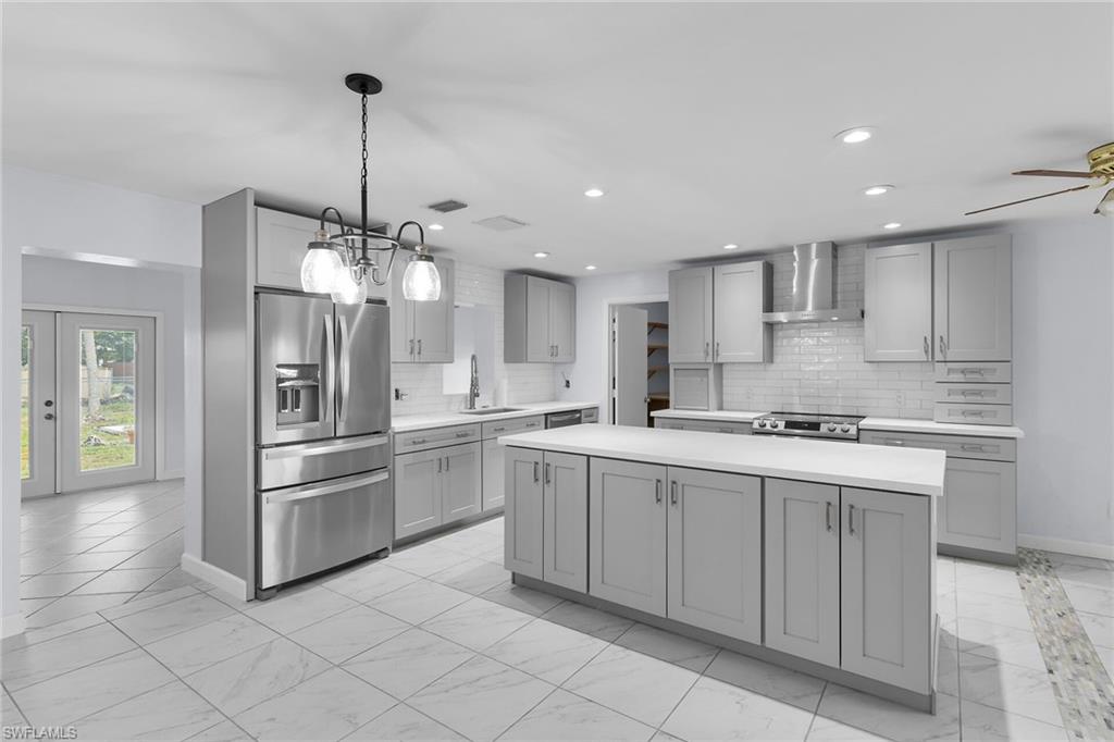 4502 22nd Place Southwest Naples, FL 34116 - Photo 8 of 30 Kitchen featuring appliances with stainless steel finishes, light countertops, gray cabinets, a center island, and light marble finish flooring