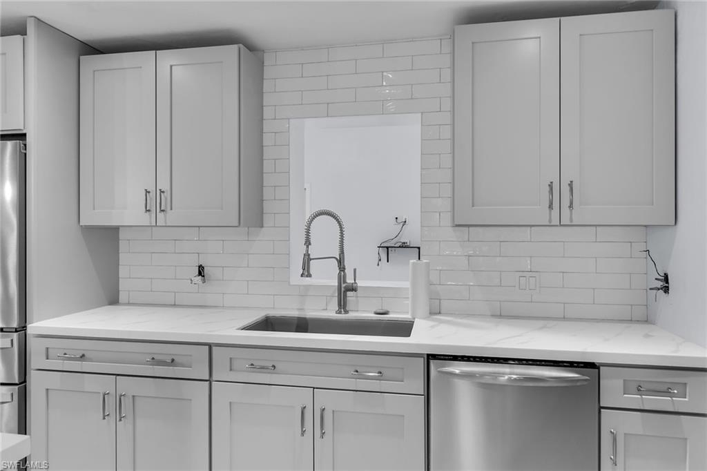 4502 22nd Place Southwest Naples, FL 34116 - Photo 10 of 30 Kitchen featuring appliances with stainless steel finishes, light stone counters, and decorative backsplash