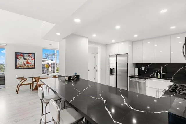 a kitchen with stainless steel appliances granite countertop a dining table chairs and refrigerator