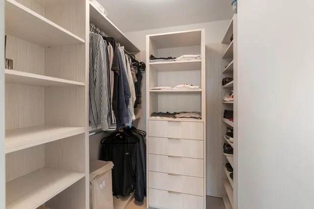 a view of walk in closet with clothes and shoes