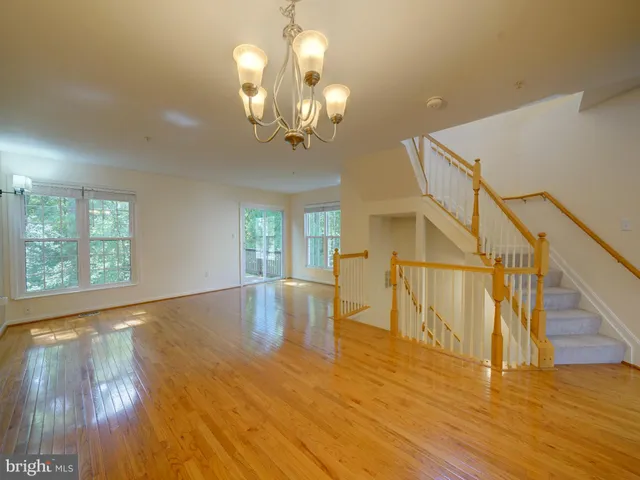 a view of a room with wooden floor chandelier and windows