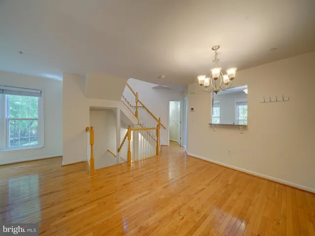 a view of a room with wooden floor staircase and a chandelier