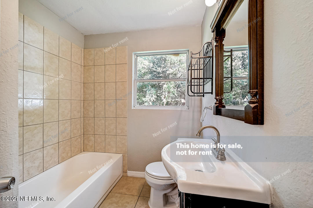3503 Rogero Road Jacksonville, FL 32277 - Photo 24 of 27 a bathroom with a sink a toilet a mirror and shower