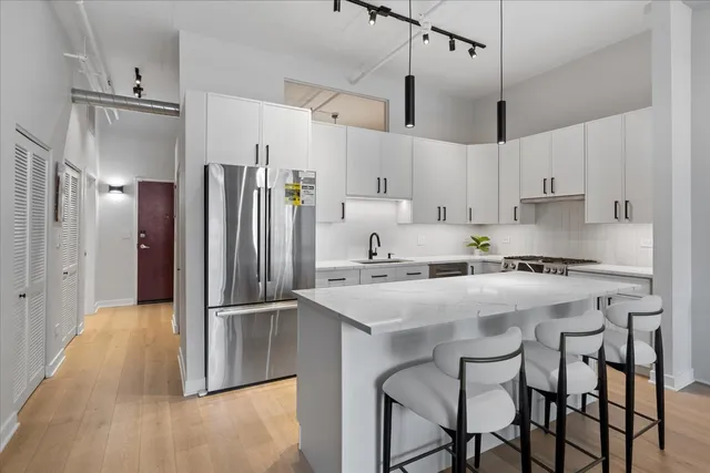 a kitchen with stainless steel appliances a refrigerator a stove a sink and white cabinets