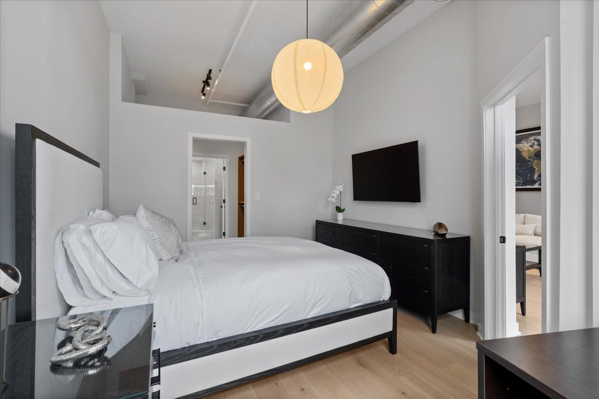 740 West Fulton Street, Unit 507 Chicago, IL 60661 - Photo 15 of 27 a bedroom with a bed and a flat tv screen on dresser