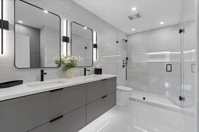 a bathroom with a double vanity sink toilet mirror and shower