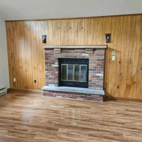 a view of an empty room with wooden floor and a fireplace