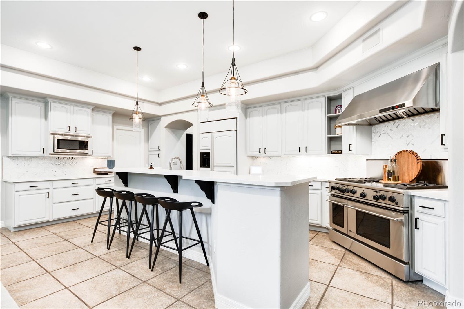 1 Ravenswood Road Cherry Hills Village, CO 80113 - Photo 14 of 40 a kitchen with stainless steel appliances a stove a sink dishwasher a refrigerator white cabinets and chairs with wooden floor