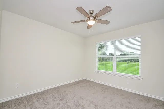 an empty room with a chandelier fan and windows