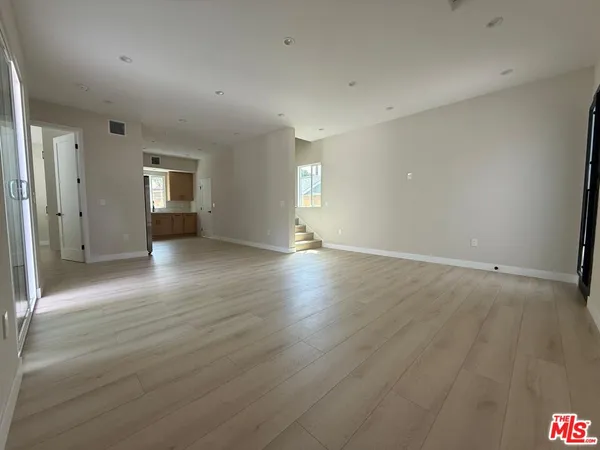 a view of a refrigerator in kitchen and an empty room