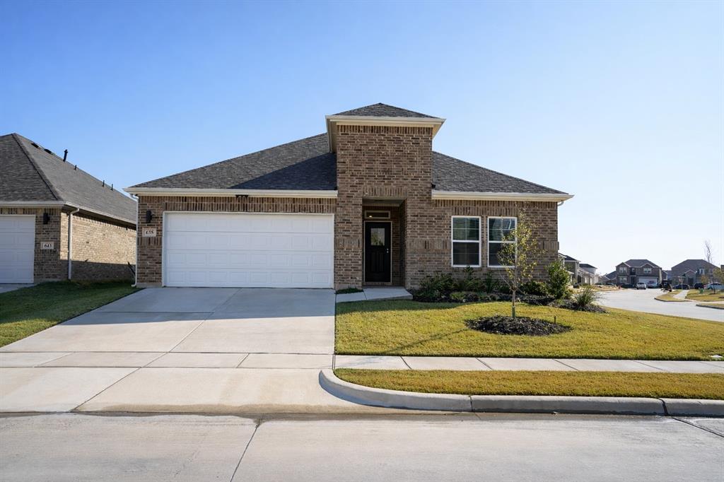 View of front of home with brick siding, a front lawn, a shingled roof, driveway, and an attached garage