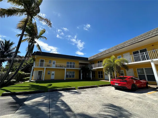 a front view of a house with a yard and potted plants