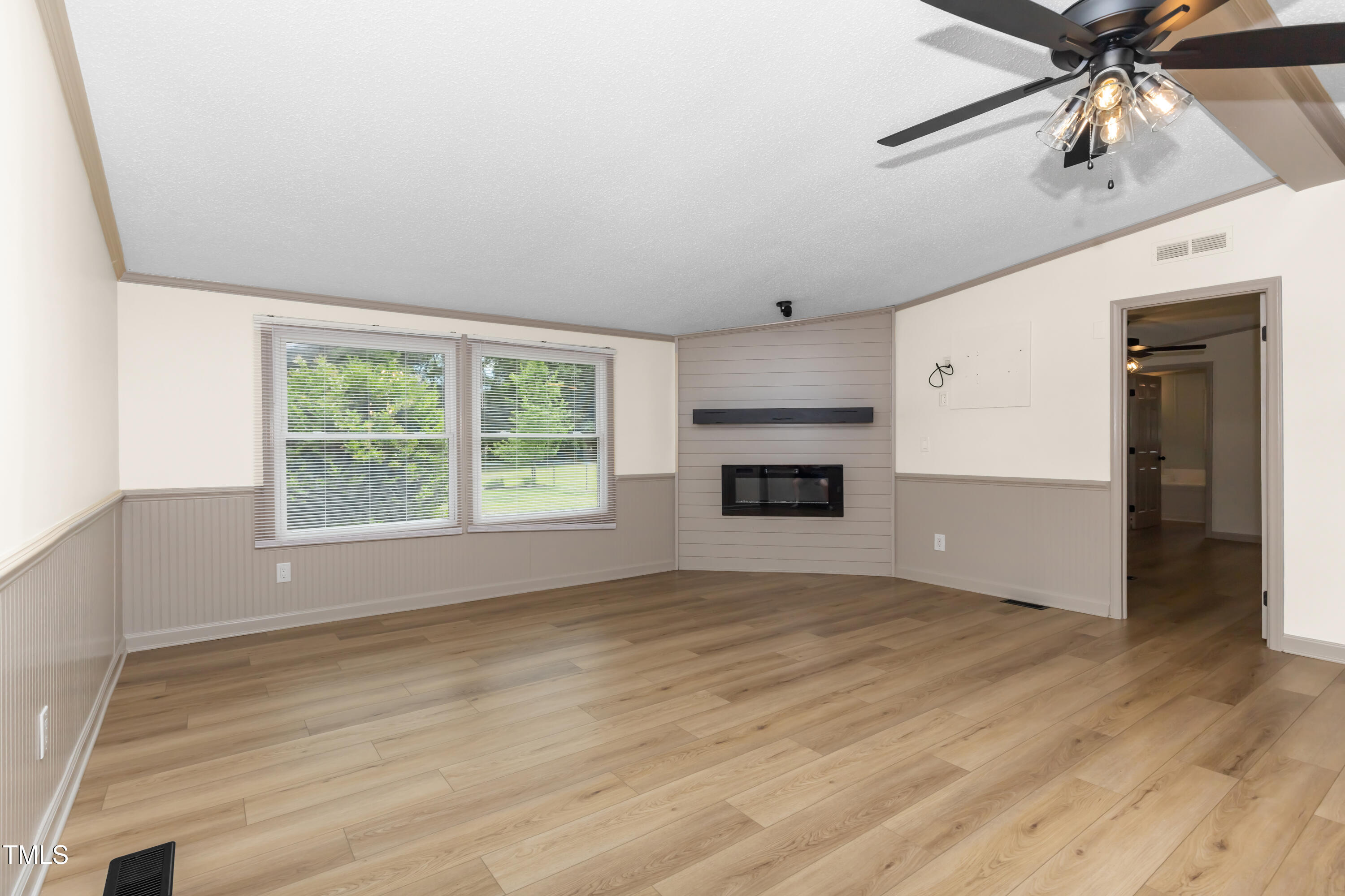 165 Dawn Road Benson, NC 27504 - Photo 4 of 30 an empty room with windows chandelier fan and a fireplace