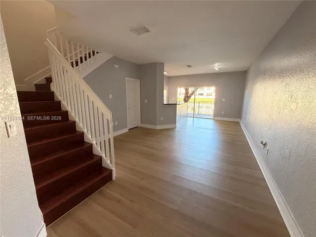 a view of a hallway with wooden floor and stairs