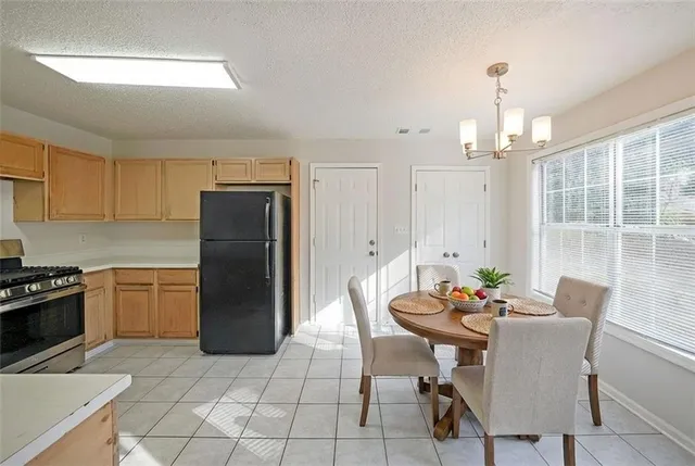 a kitchen with a dining table chairs and refrigerator