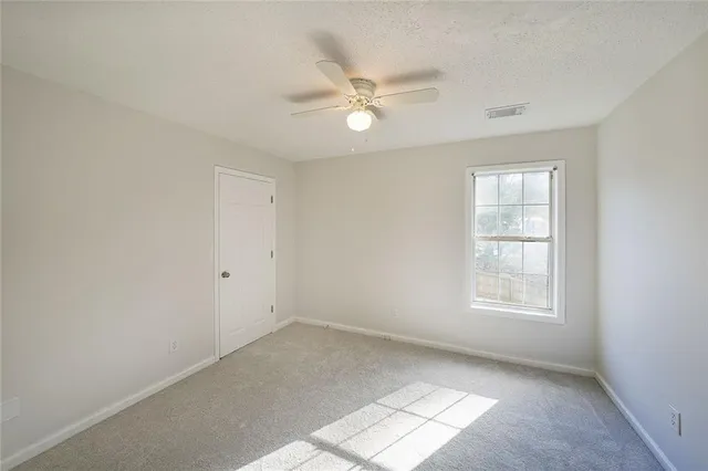an empty room with windows and fan