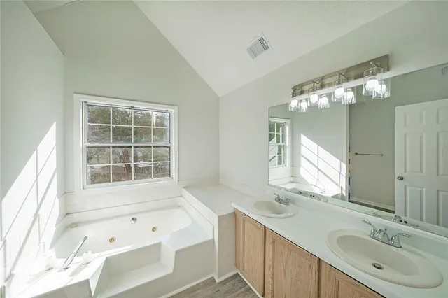a bathroom with a tub sink and mirror