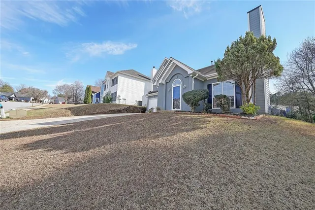 a front view of a house with a yard and large tree