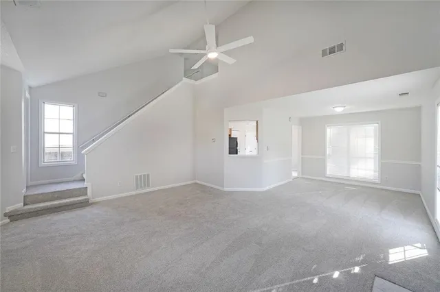 an empty room with windows and ceiling fan