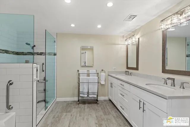 a spacious bathroom with double vanity a mirror and shower