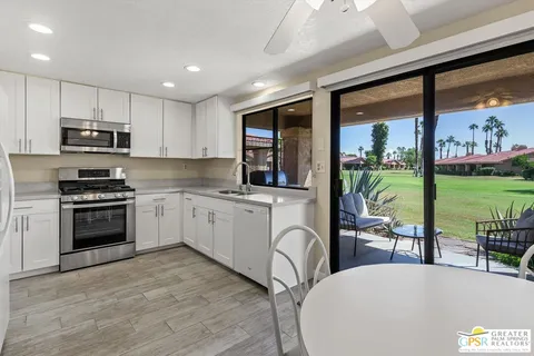 a kitchen with stainless steel appliances kitchen island granite countertop a stove and a view of living room with a flat screen tv