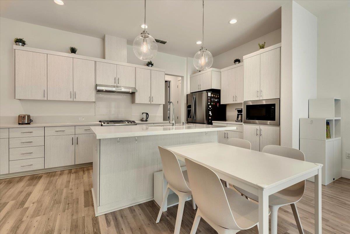 7961 Regional Common Dublin, CA 94568 - Photo 6 of 40 a kitchen with a table a sink cabinets and stainless steel appliances