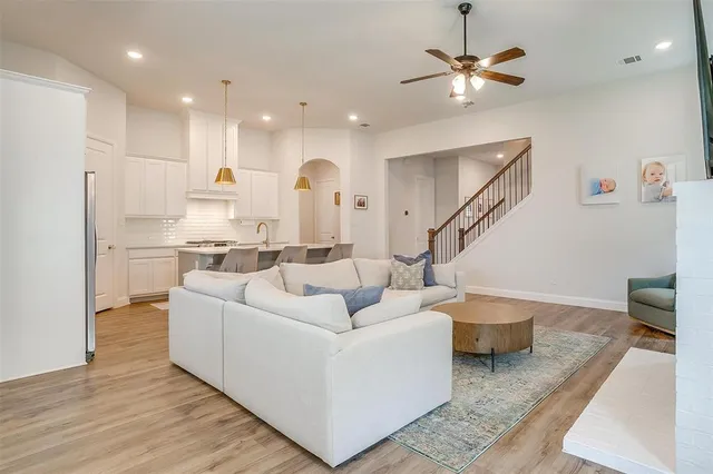 a living room with couches chairs and kitchen view with wooden floor