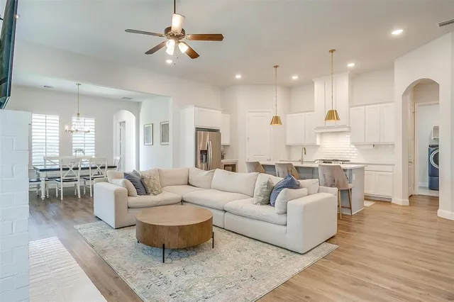 a living room with furniture kitchen view and a chandelier