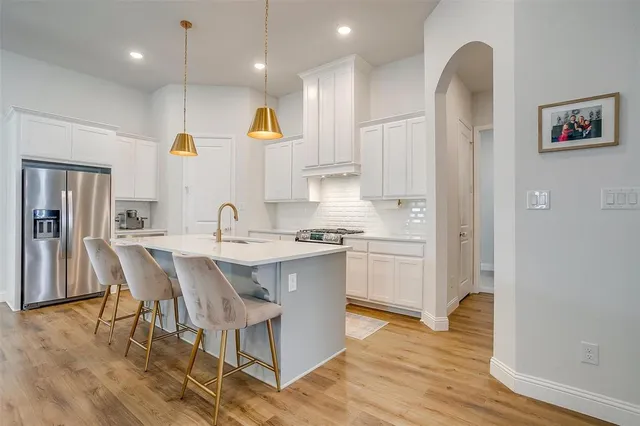 a kitchen with stainless steel appliances granite countertop a sink a stove a refrigerator and island with wooden floor