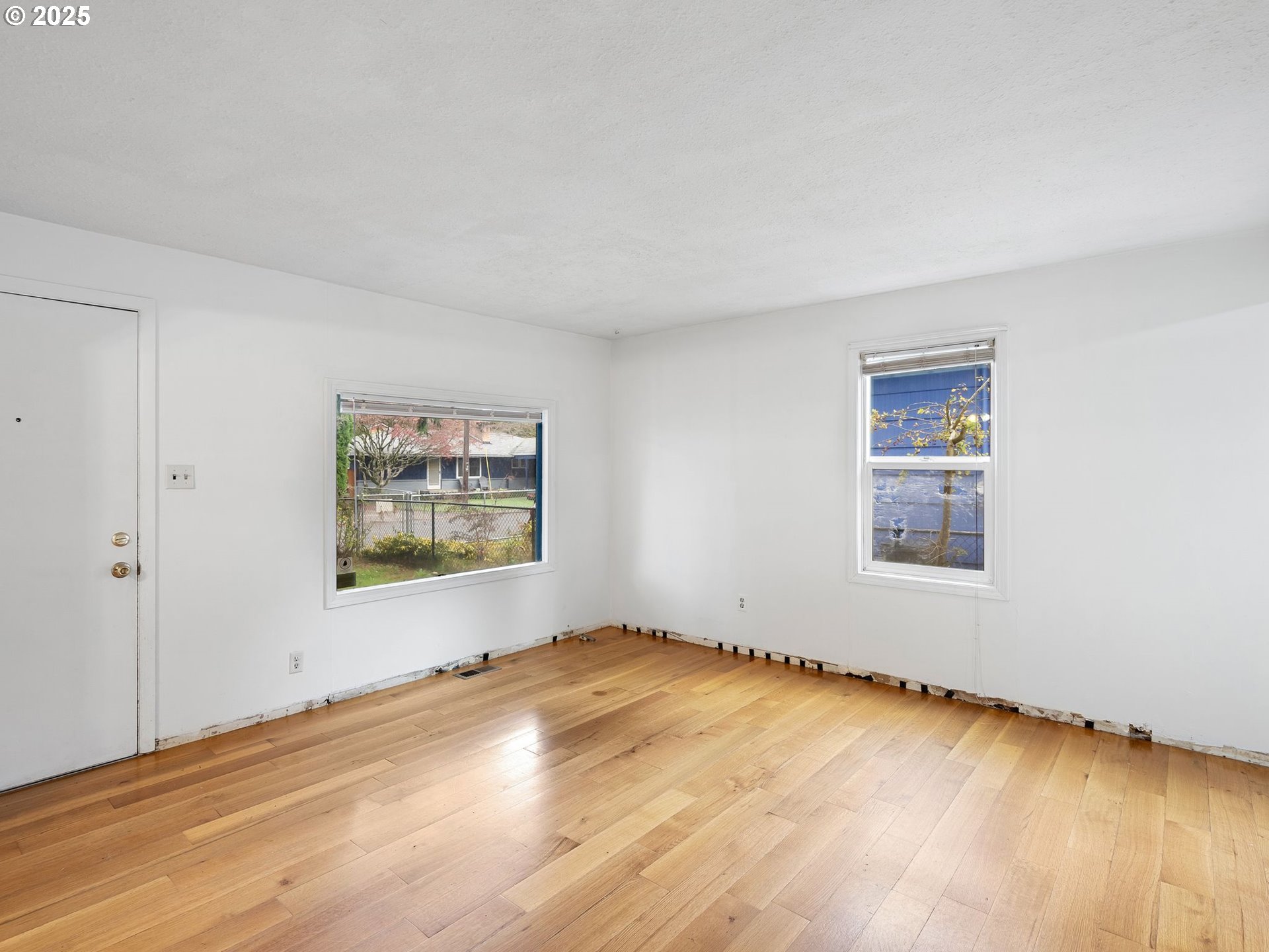 6009 Southeast 138th Place Portland, OR 97236 - Photo 5 of 37 a view of an empty room with a window and wooden floor