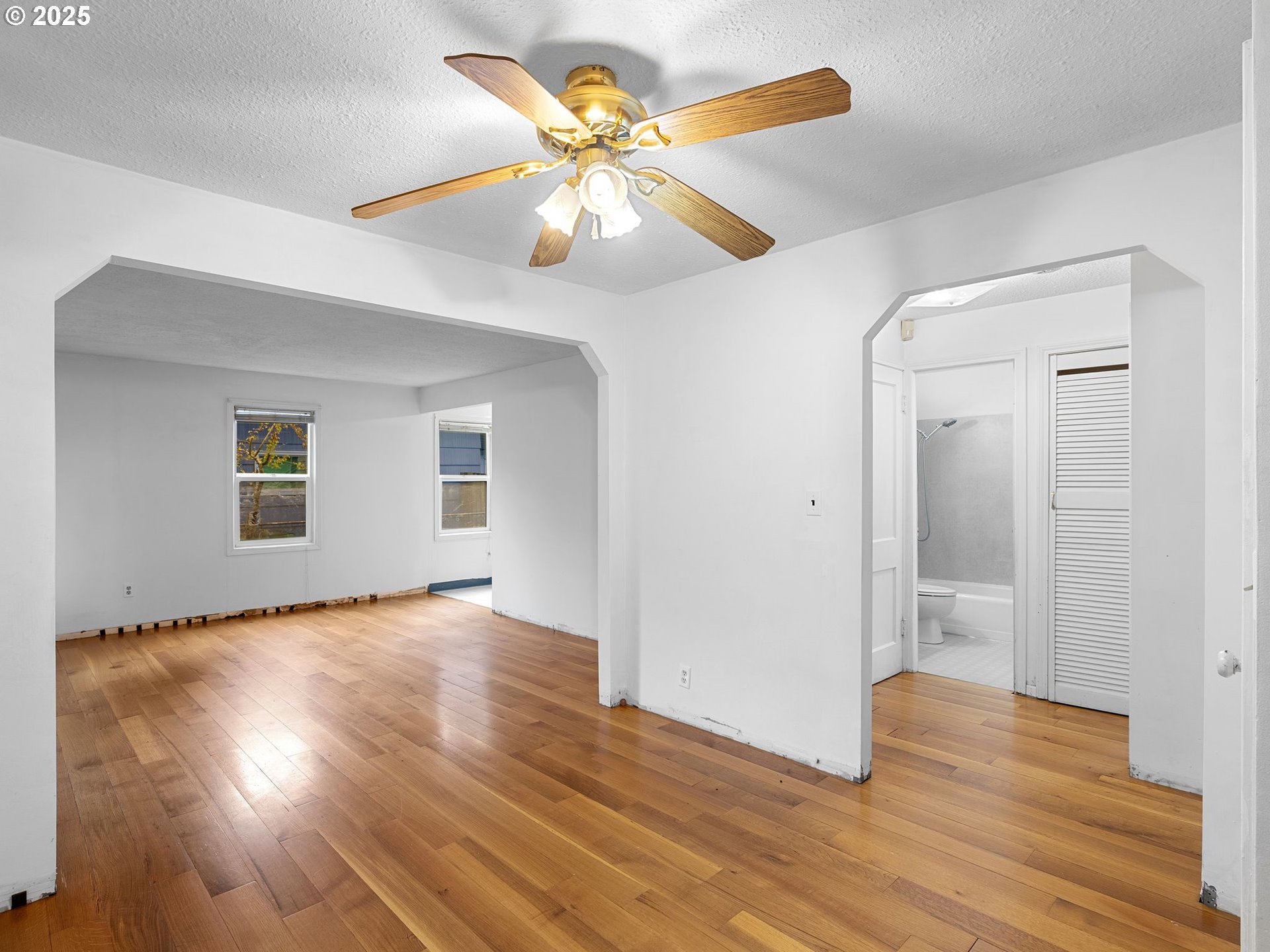 6009 Southeast 138th Place Portland, OR 97236 - Photo 8 of 37 an empty room with wooden floor and a ceiling fan