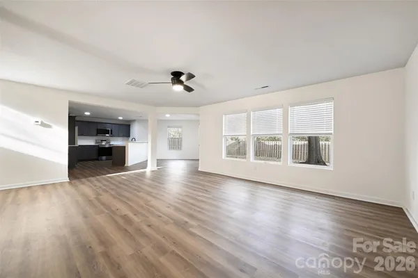 a view of empty room with wooden floor and windows