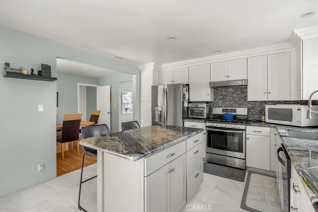 a kitchen with a refrigerator a stove a sink and white cabinets