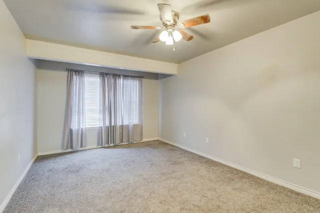 an empty room with a chandelier fan and windows