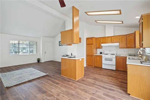 a large kitchen with stainless steel appliances granite countertop a stove a sink and a wooden floors