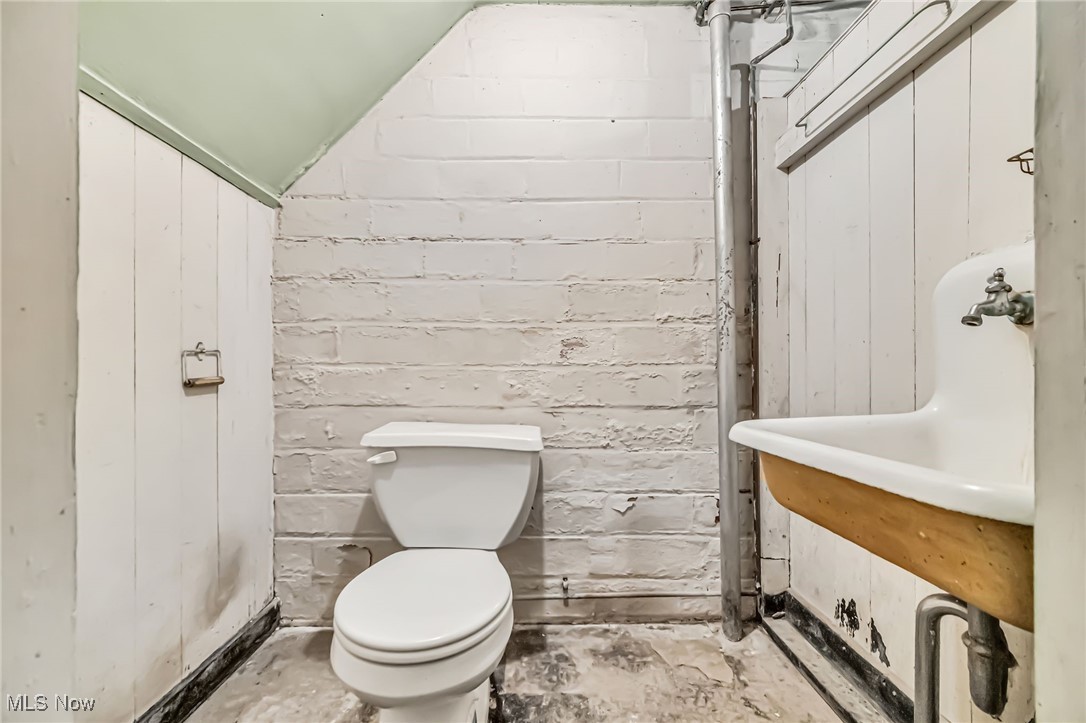 14608 Triskett Road Cleveland, OH 44111 - Photo 21 of 31 Half bath featuring lofted ceiling, wooden walls, and unfinished concrete floors
