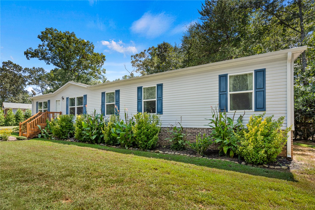 Neat siding and classic shutters define this inviting exterior framed by green landscaping.