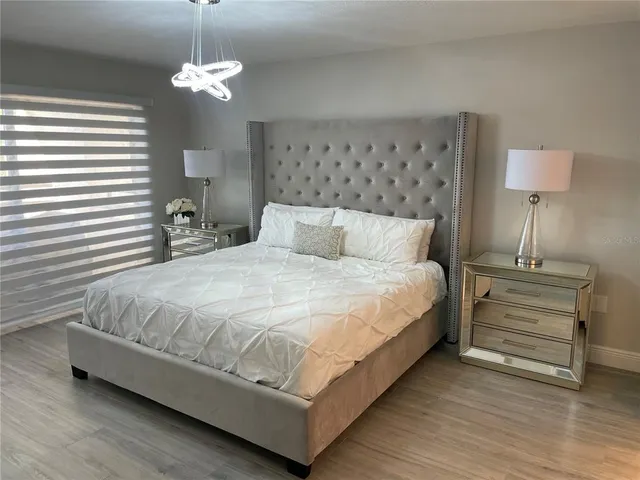 a bedroom with bed and a lamp on dresser