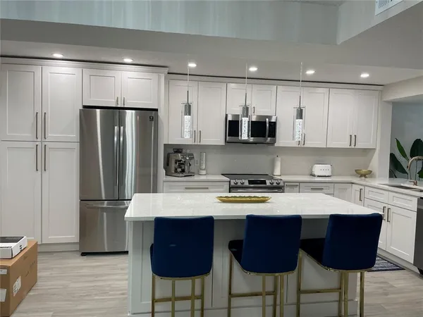 a kitchen with stainless steel appliances granite countertop a refrigerator a stove a sink and a microwave