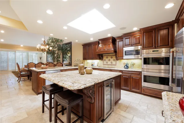 a kitchen with stainless steel appliances granite countertop a stove top oven a sink dishwasher a dining table and chairs with wooden floor