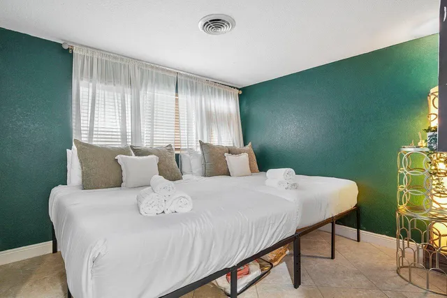 a large white bed in a room next to a window
